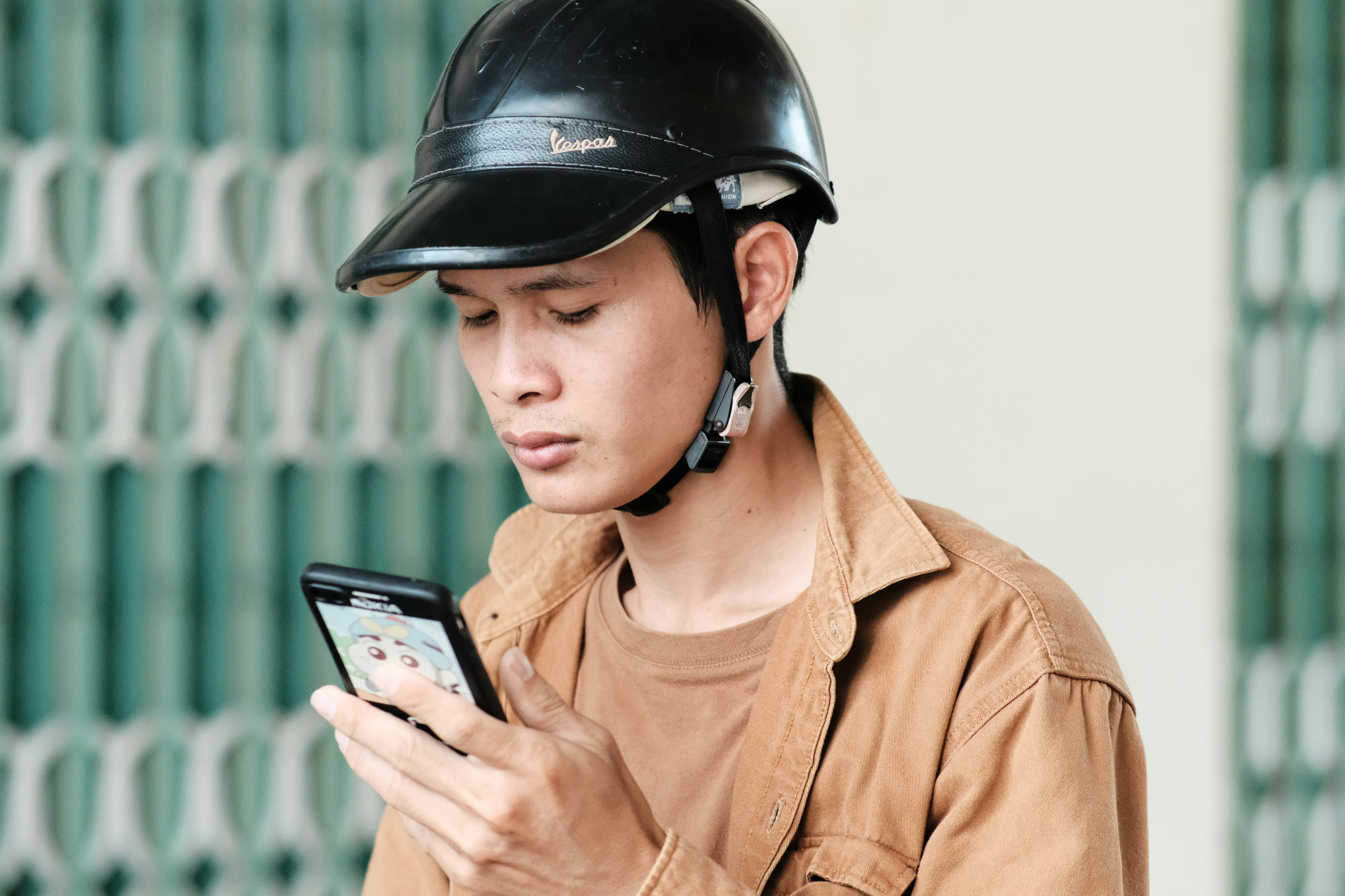 a man wearing a helmet looking at a cell phone