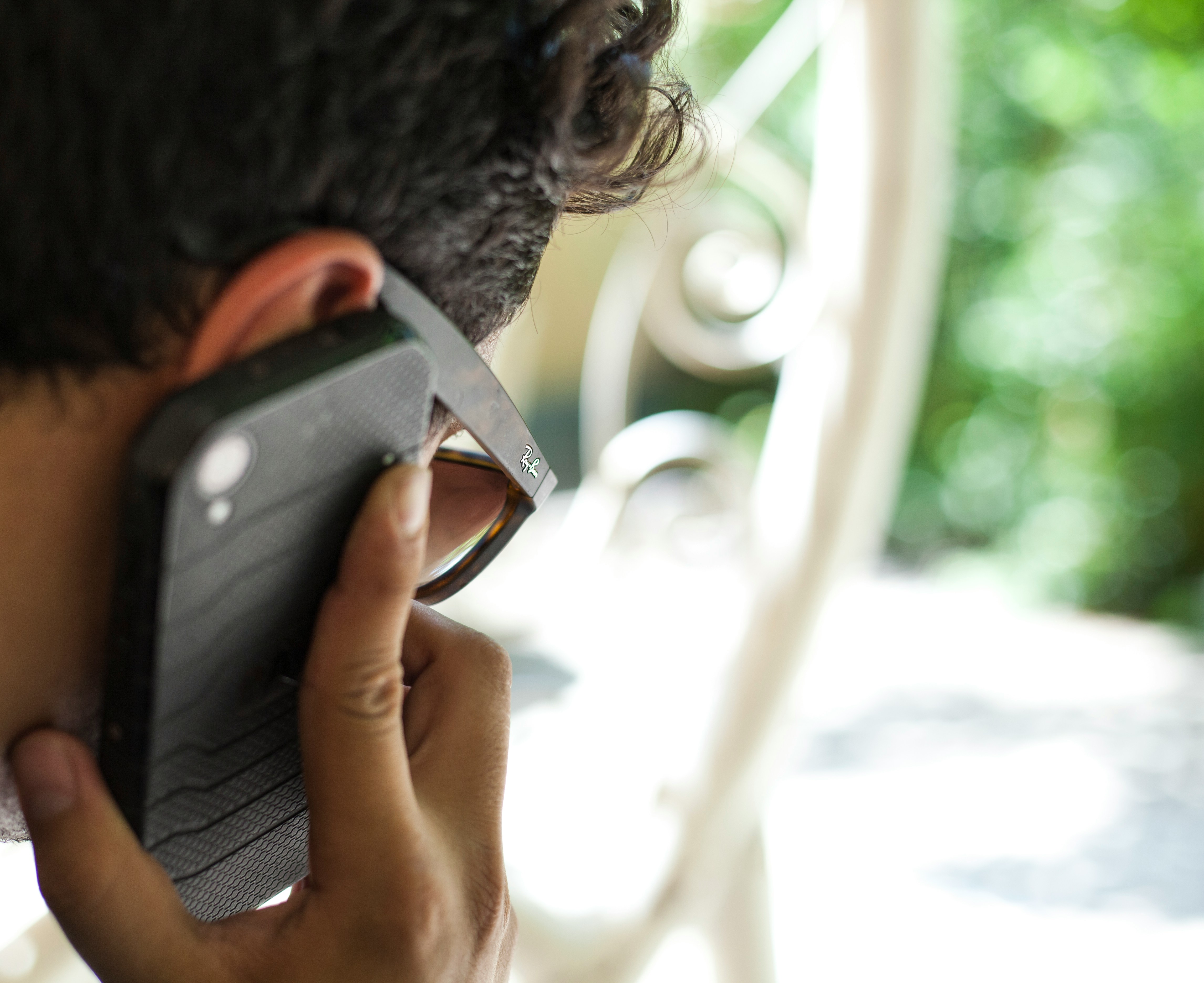 person using smartphone near white metal chair